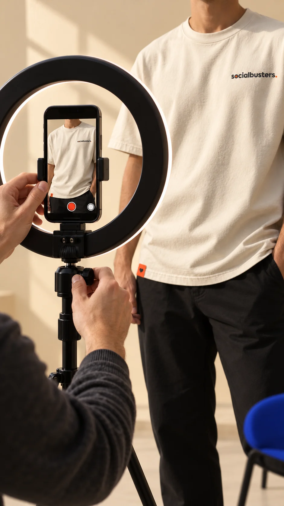 Iemand filmt met een telefoon op een statief met ringlamp een persoon in een Socialbusters-shirt