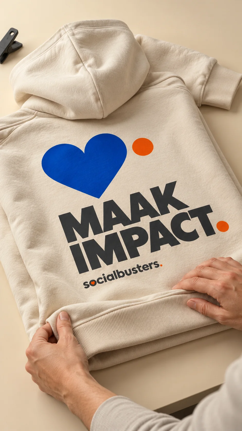 Beige hoodie met een blauw hart en de tekst Maak impact van Socialbusters