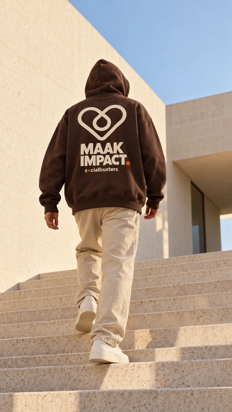 Iemand van achteren op een trap in een bruine hoodie met een groot hart en de tekst Maak impact.